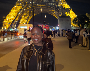 Kimberlee John in front of the Eiffel Tower at night
