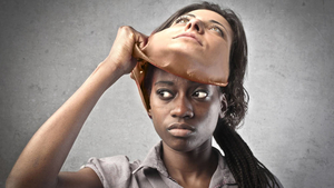 Black woman pulling off a mask depicting a white womans face - Racial prejudice