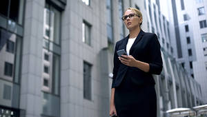 a woman in a suit looking at the horizon in the middle of buildings