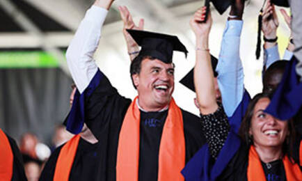 Un groupe de diplômés, vêtus de robes de graduation et tenant fièrement leurs chapeaux en l'air. 