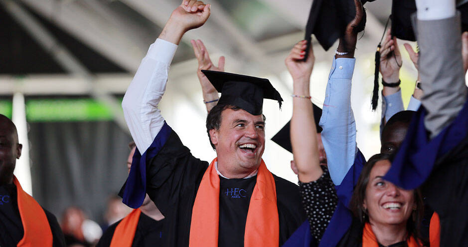 Un groupe de diplômés, vêtus de robes de graduation et tenant fièrement leurs chapeaux en l'air