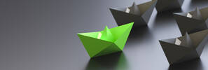 bateau en papier vert devant d'autres bateaux gris